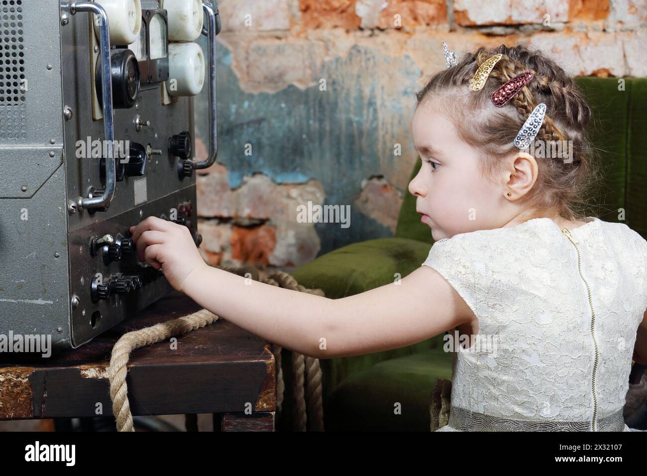 La bambina configura la fonte di alimentazione al ricevitore radio in una casa molto vecchia. Foto Stock