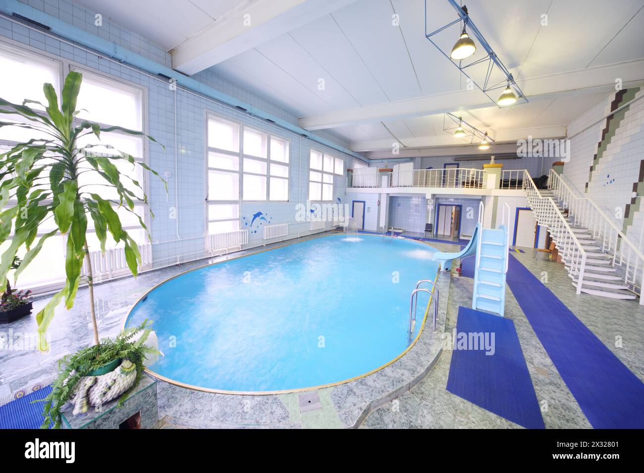 Piscina coperta ovale vuota con un piccolo scivolo e acqua pulita Foto Stock