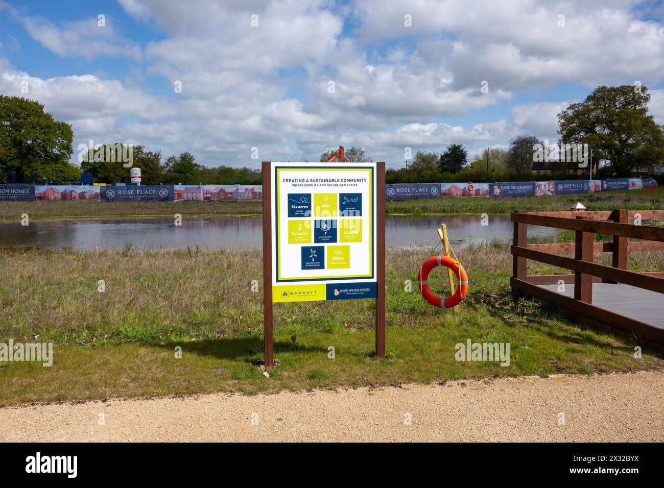 Un cartello accanto a un lago artificiale su un cantiere edile che dice che lo sviluppatore sta cercando di creare una comunità sostenibile. Foto Stock