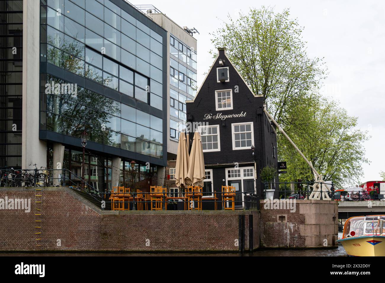 Il caffè de Sluyswacht in una vecchia casa tortuosa a Jodenbreestraat è qui dal 1685, ex cottage dei custodi delle chiuse, visto dalla nave da crociera sui canali di Amsterdam Foto Stock