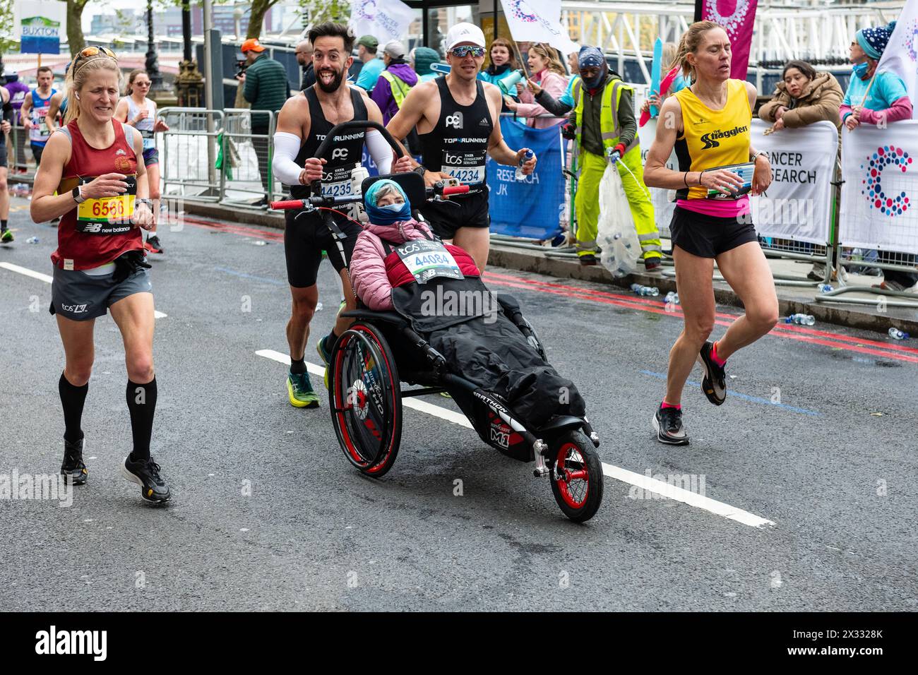 Eric Domingo Roldán spinge sua madre Sylvia sulla sua sedia a rotelle, per aiutare a diffondere la consapevolezza per la sclerosi multipla, Maratona di Londra 2024 Foto Stock