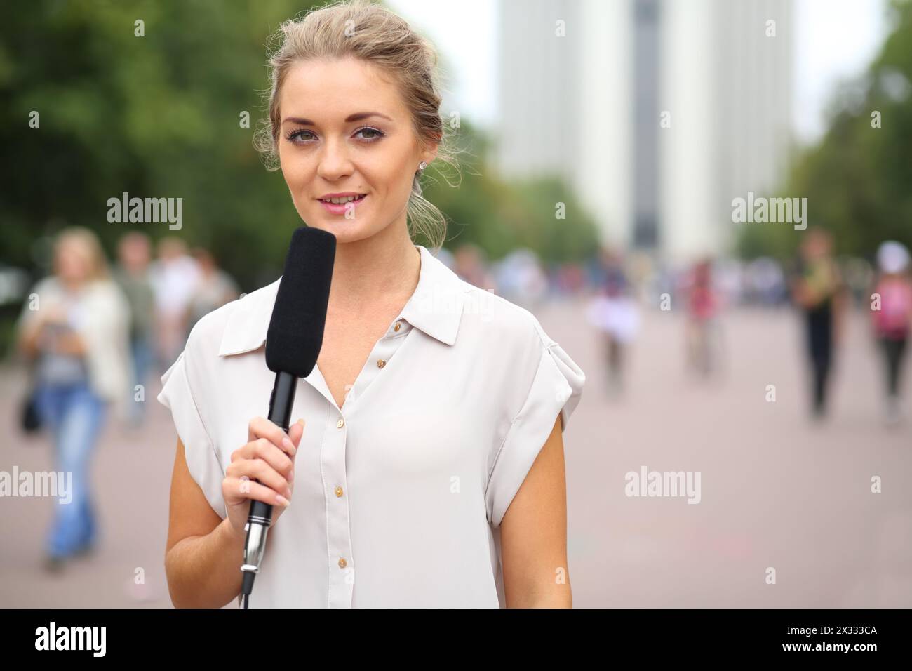 Reporter professionista bella ragazza in piedi per strada con un microfono in mano Foto Stock