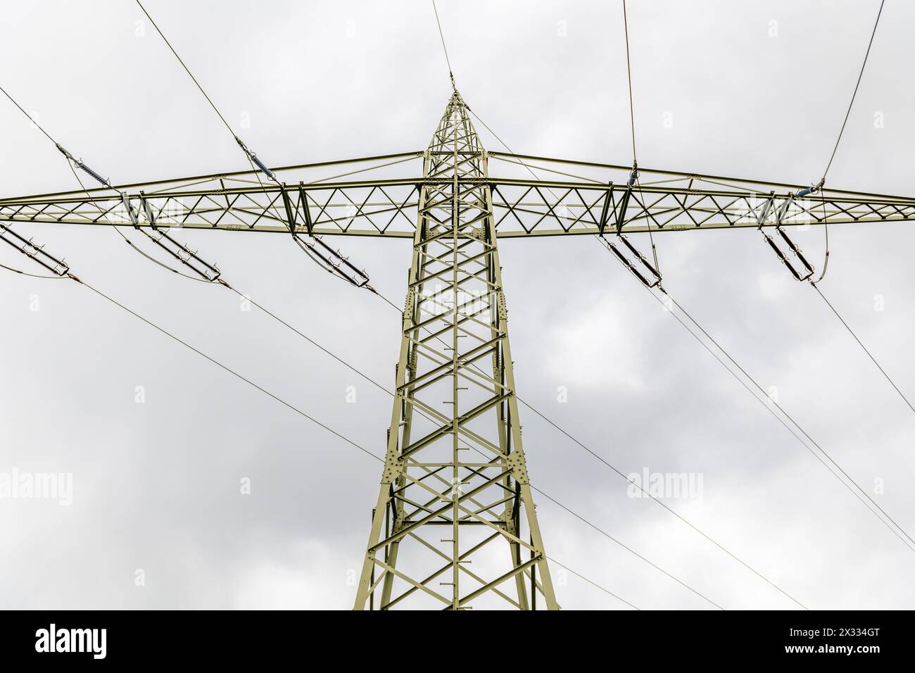 piegare la linea elettrica aerea per l'elettricità fotografata dal basso nella sezione sottostante e sui lati di fronte a un cielo grigio nuvoloso Foto Stock