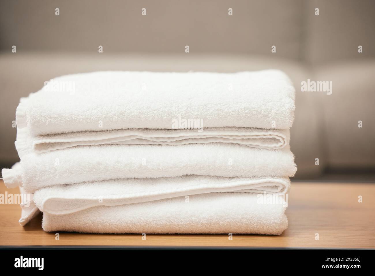 Pulito, lavanderia e asciugamano morbido sul tavolo per ospitalità, servizio di pulizia e materiale bianco di tessuto. Tessuti freschi e pile di stoffe di lino a casa Foto Stock