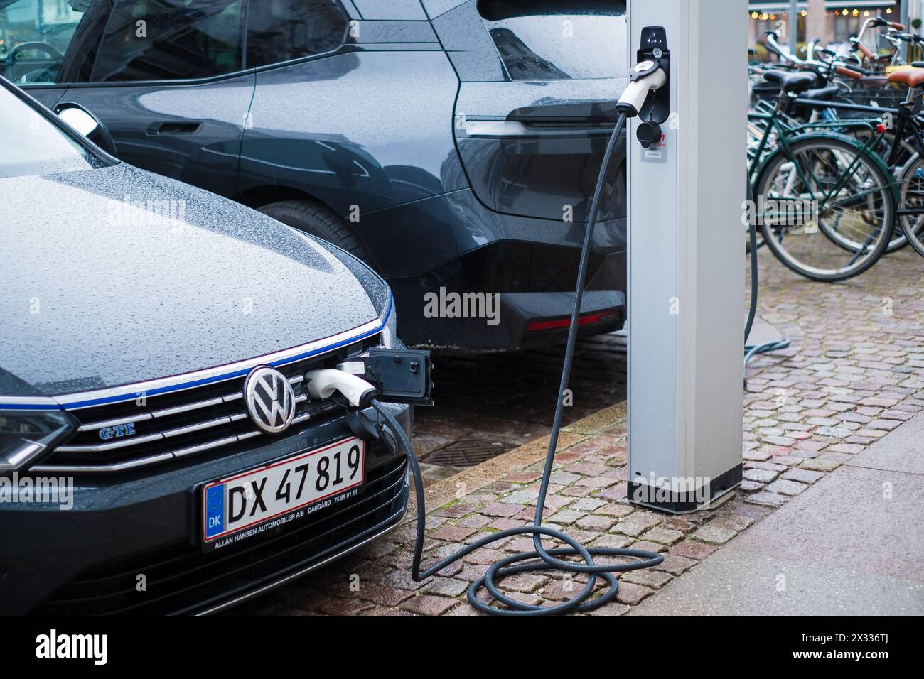 Copenaghen, Danimarca - 6 aprile 2024: Veicolo elettrico parcheggiato in strada e in carica. Foto Stock