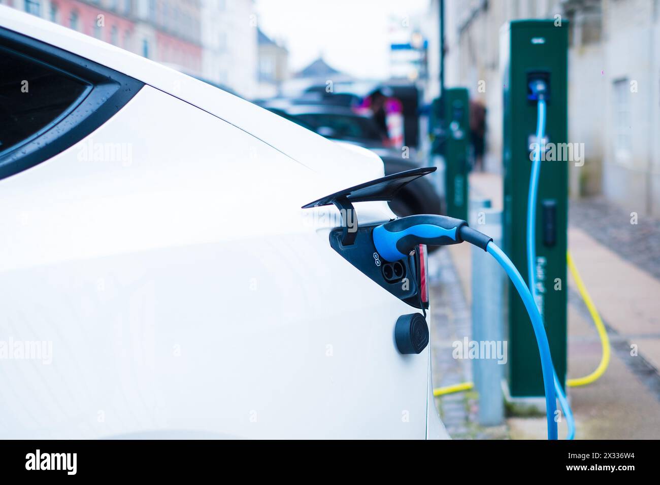 Veicolo elettrico parcheggiato su strada e in carica. Foto Stock