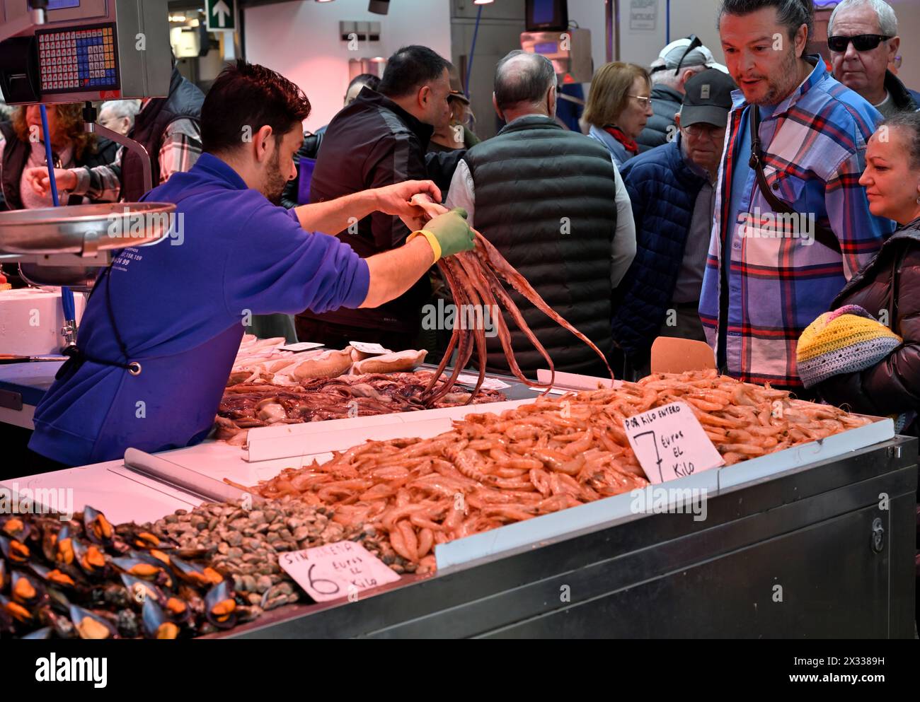 Alimento di mare fresco in vendita sul mercato stalla con venditore che detiene polpo Foto Stock