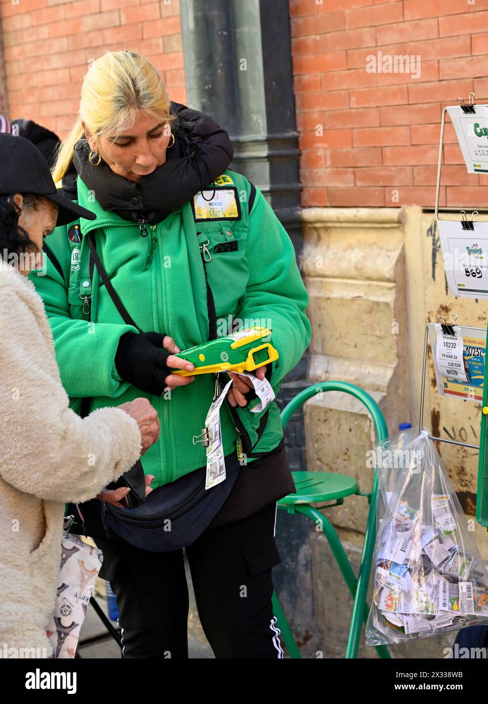 Venditore ufficiale di una donna di biglietti della lotteria con cliente e biglietti in vendita per un certo numero di lotterie diverse, Malaga, Spagna Foto Stock