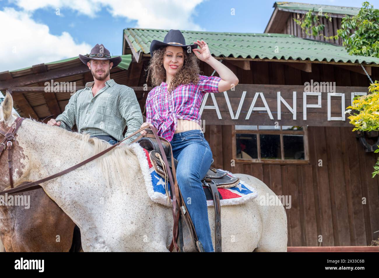 coppia di cowboy a cavallo vicino a casa Foto Stock