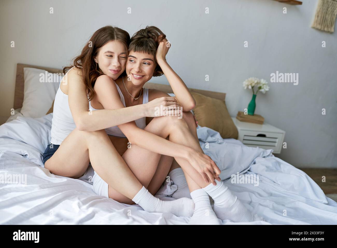 Due donne si rilassano su un letto con un abbigliamento accogliente. Foto Stock
