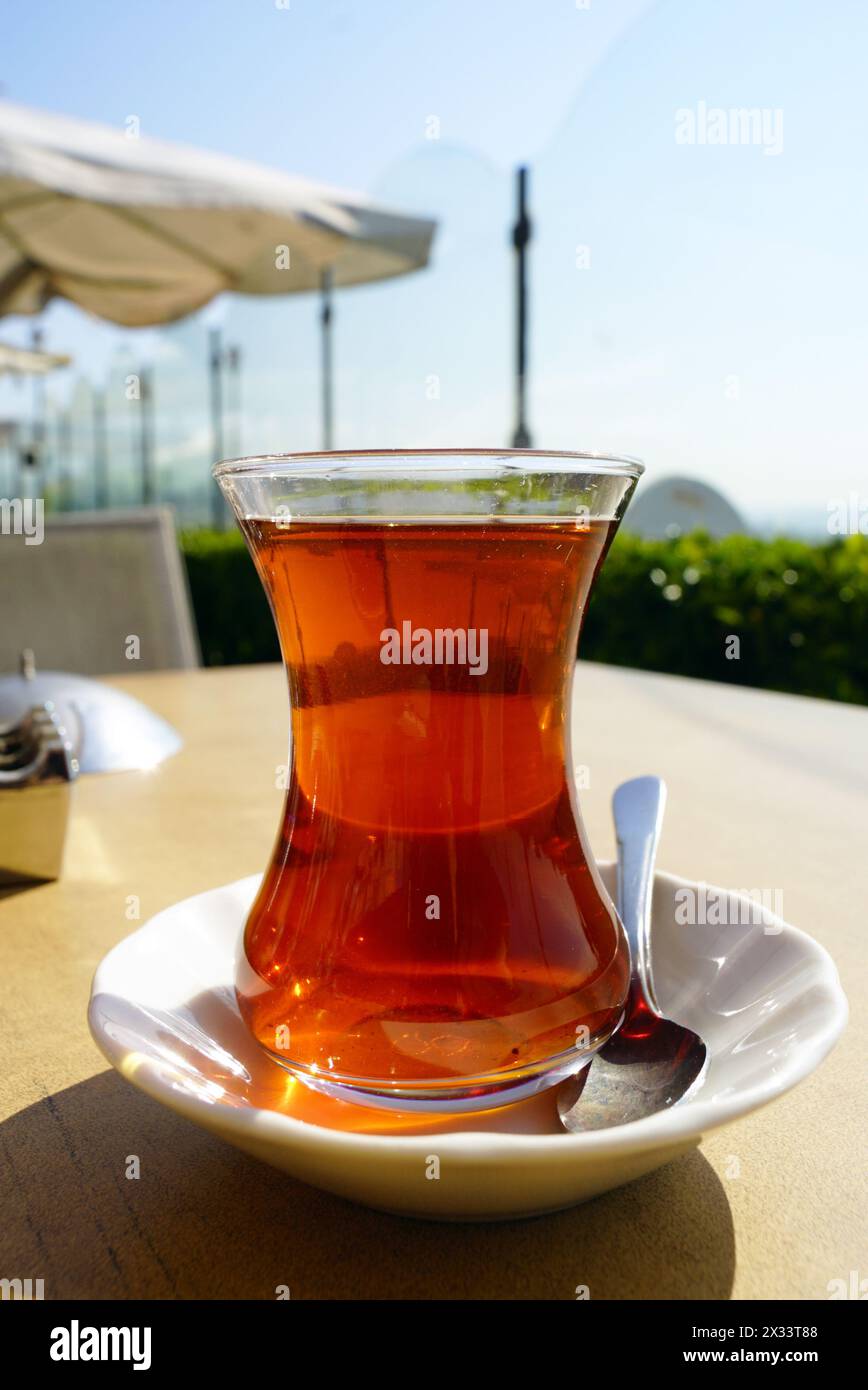 Tè nero in un tradizionale bicchiere turco, in piedi sul tavolo di un caffè di strada a Istanbul Foto Stock