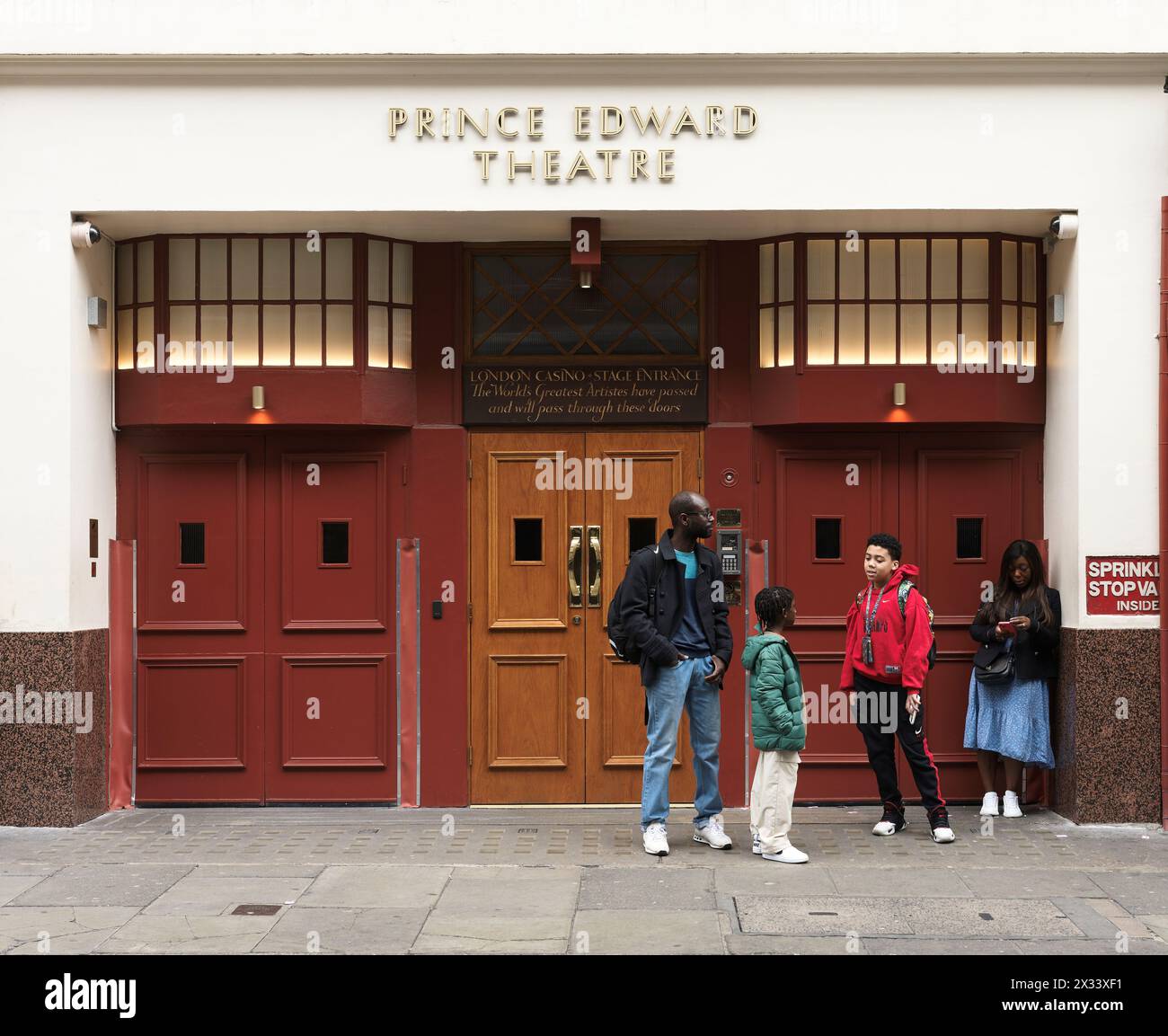 Una famiglia attende fuori dall'ingresso del palcoscenico del London Casino al teatro Prince Edward (un luogo in cui Mozart visse, suonò e si esibì nel 1764-5), Foto Stock