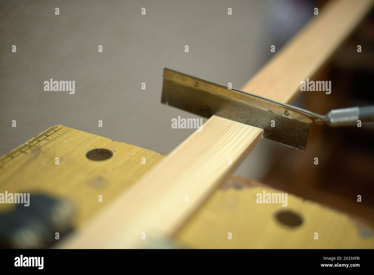 Immagine ravvicinata di una sega che taglia un pezzo di legno in un'officina catturando l'essenza del lavoro manuale e della lavorazione del legno. Foto Stock