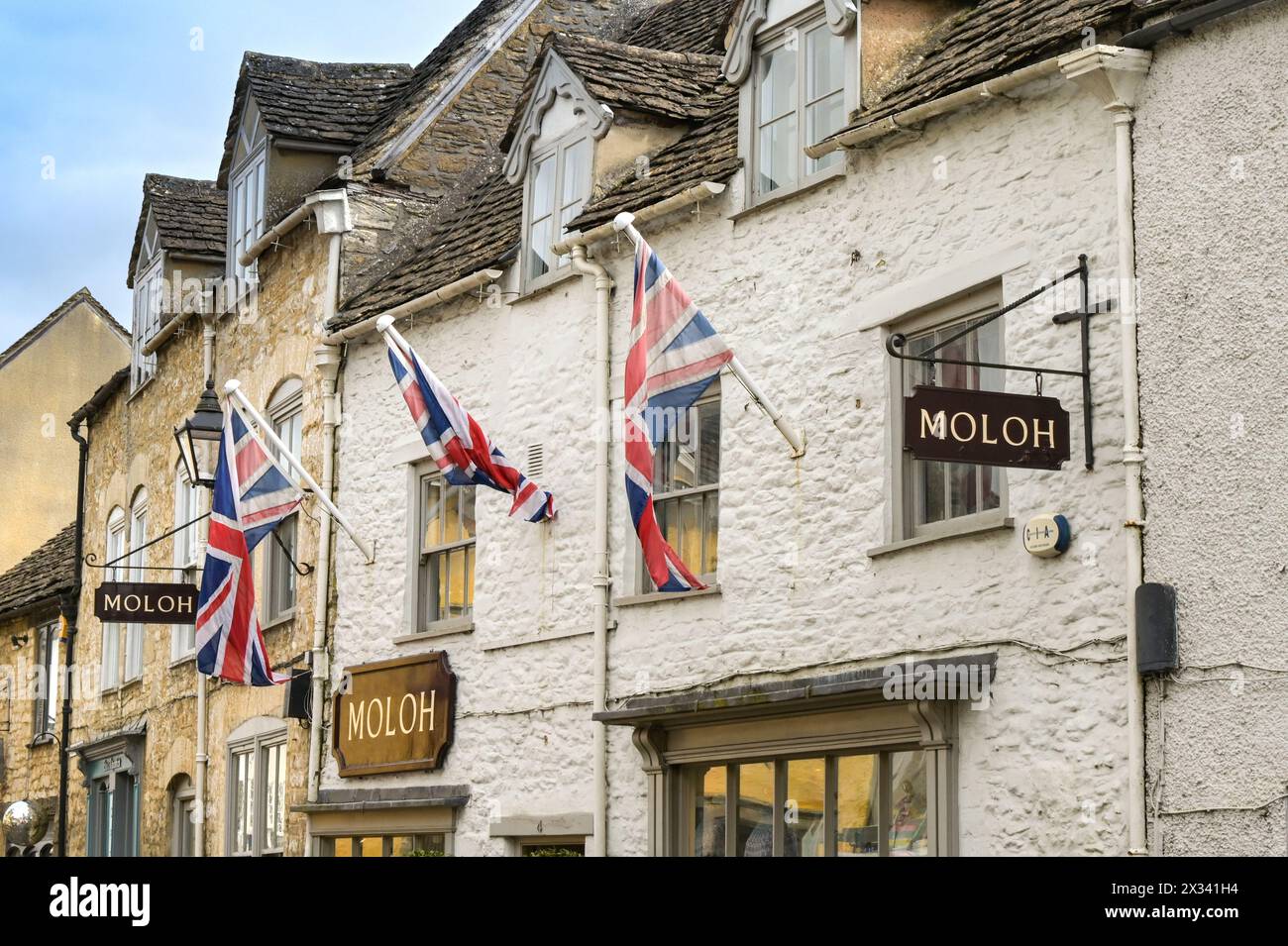 Tetbury, Gloucestershire, Inghilterra, Regno Unito - 13 aprile 2024: Union Jack batte le bandiere sopra i negozi nel centro della città della storica città rurale di Tetbury. Foto Stock