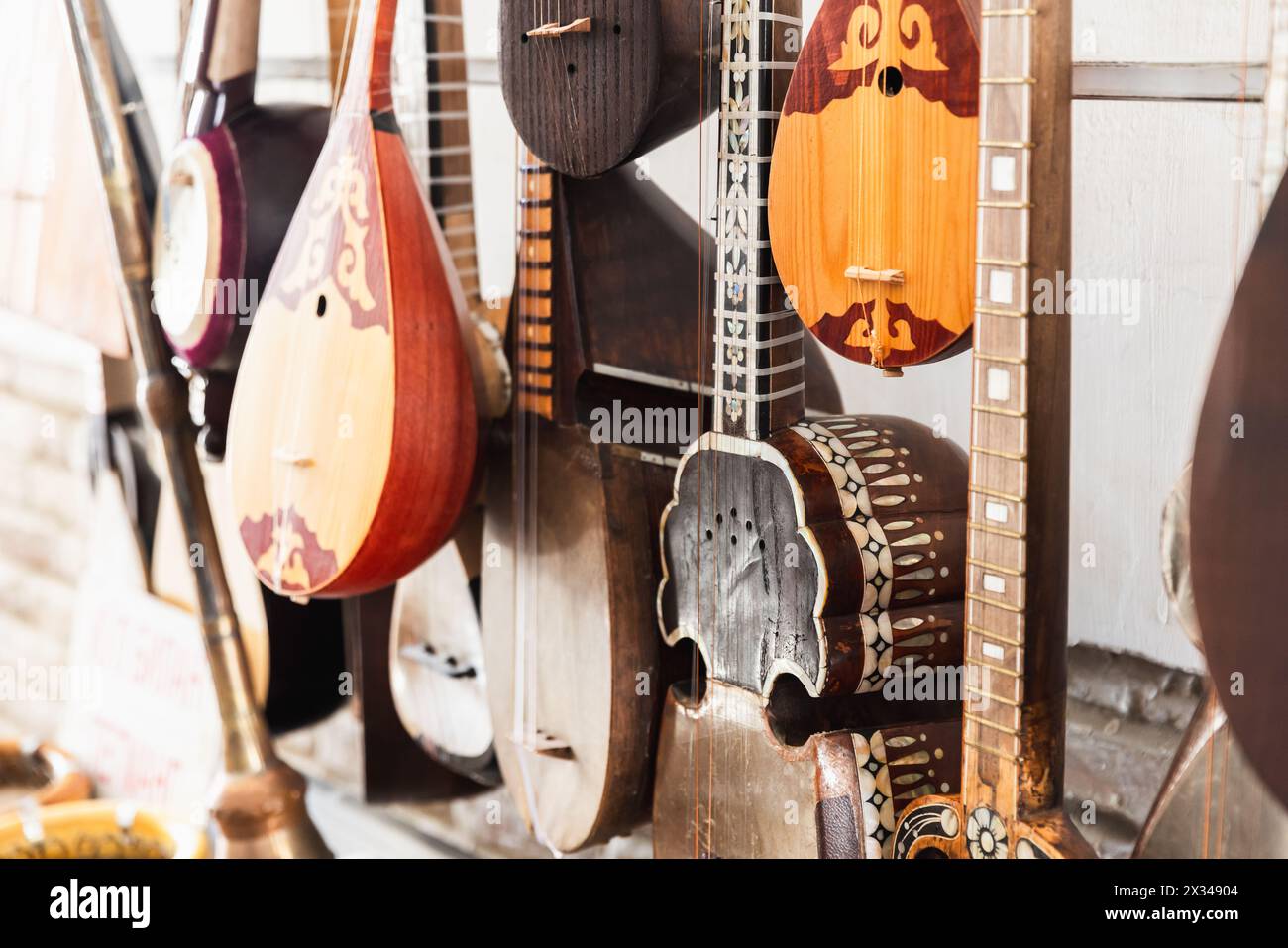 Una varietà di strumenti musicali a corde dell'Asia centrale sono messi in vendita in un bazar di Bukhara, foto ravvicinata con una messa a fuoco morbida e selettiva Foto Stock