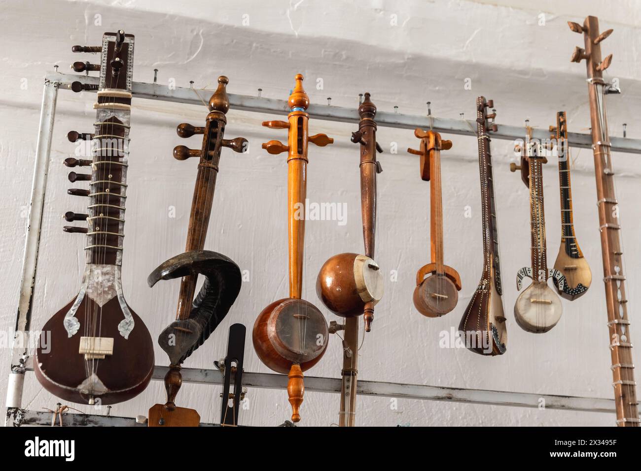 Una varietà di strumenti musicali a corde dell'Asia centrale sono messi in vendita in un bazar di Bukhara Foto Stock