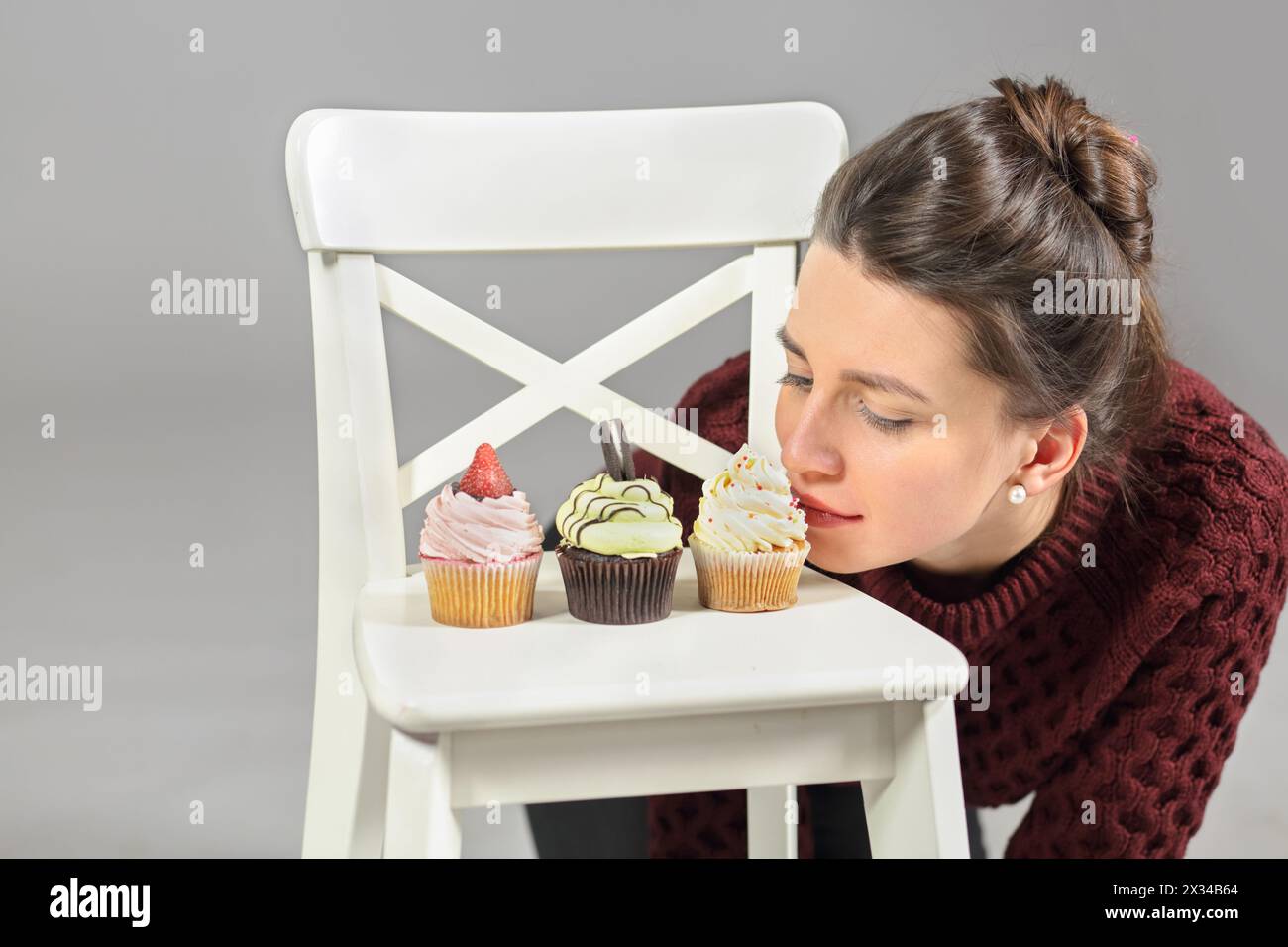 Tre torte stanno su una sedia bianca, una ragazza piegata sulla torta in ginocchio Foto Stock