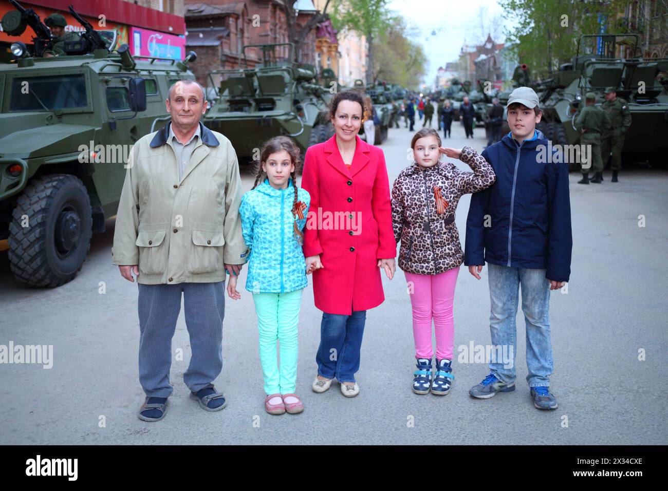 SAMARA - 6 MAGGIO 2015: Ragazzo, uomo, donna e due ragazze (con versioni di modelli) posano vicino a veicoli blindati a Samara durante le celebrazioni militari. Squar rosso Foto Stock