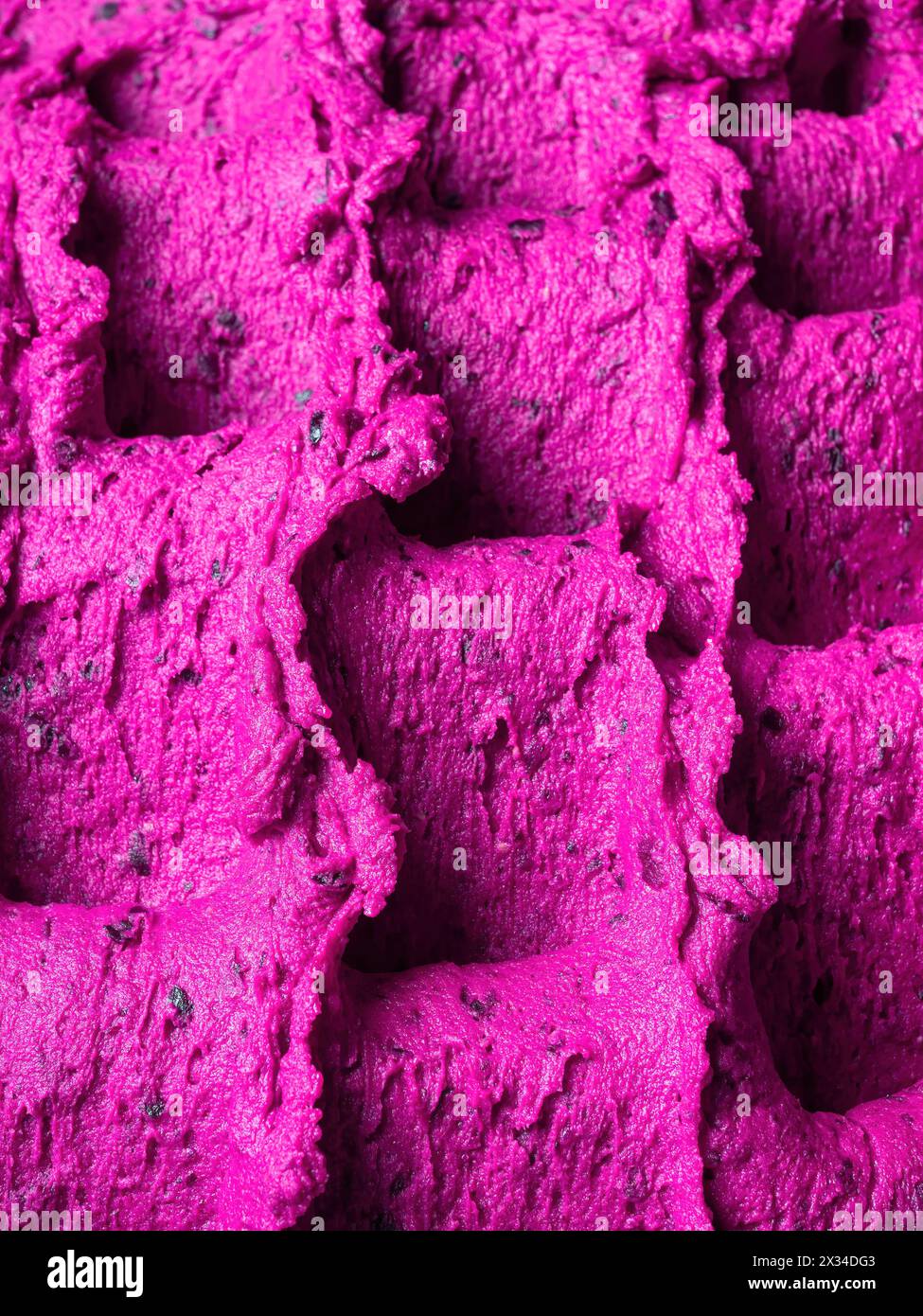 Gelato al lampone congelato - dettaglio completo del sorbetto. Primo piano di una superficie rosa di gelato riempita con pezzi di frutta mista. Foto Stock