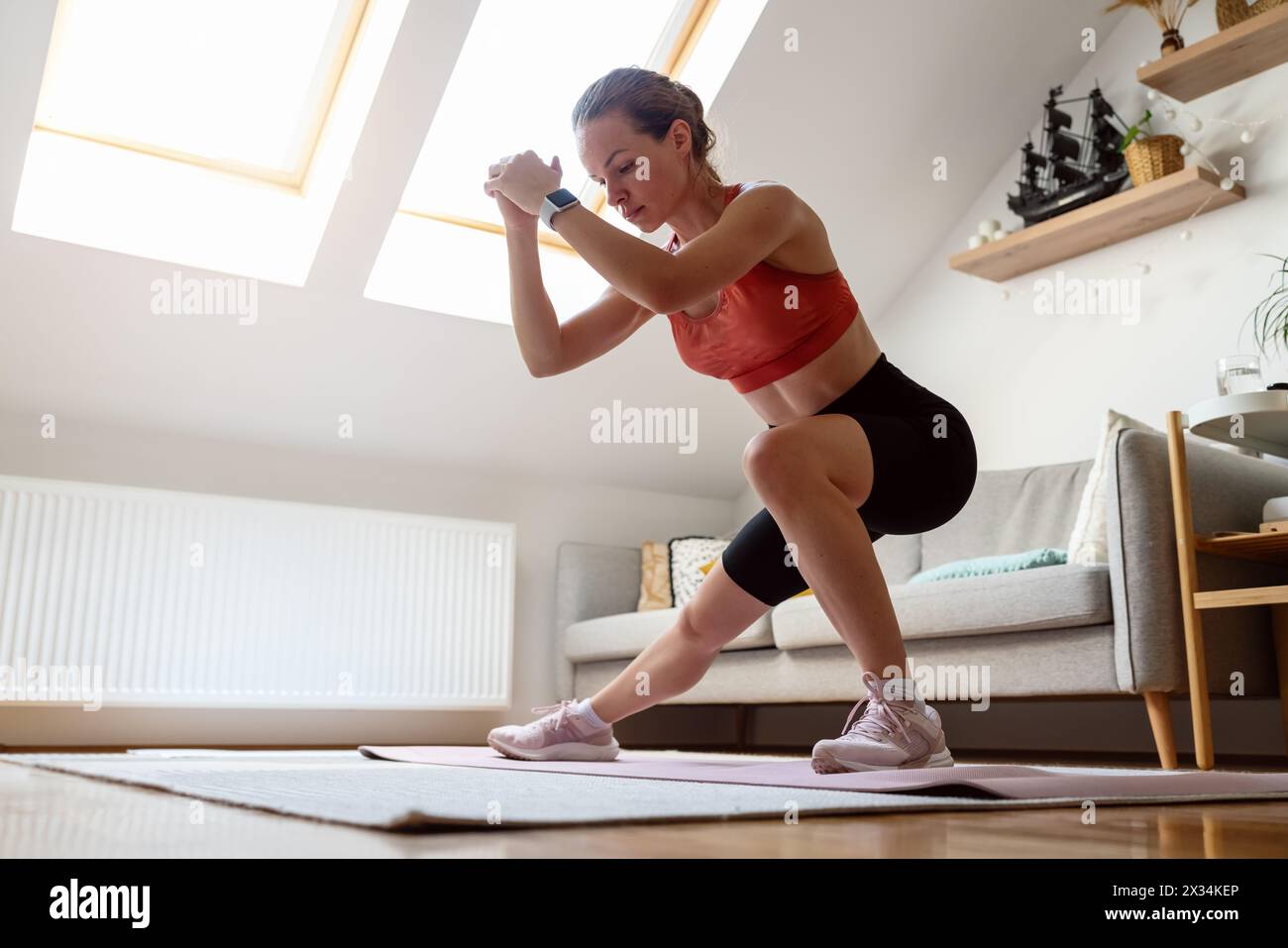 Fitness a casa. Donna atletica che fa esercizio fisico a casa. Stile di vita sportivo domestico di persone reali. Foto Stock