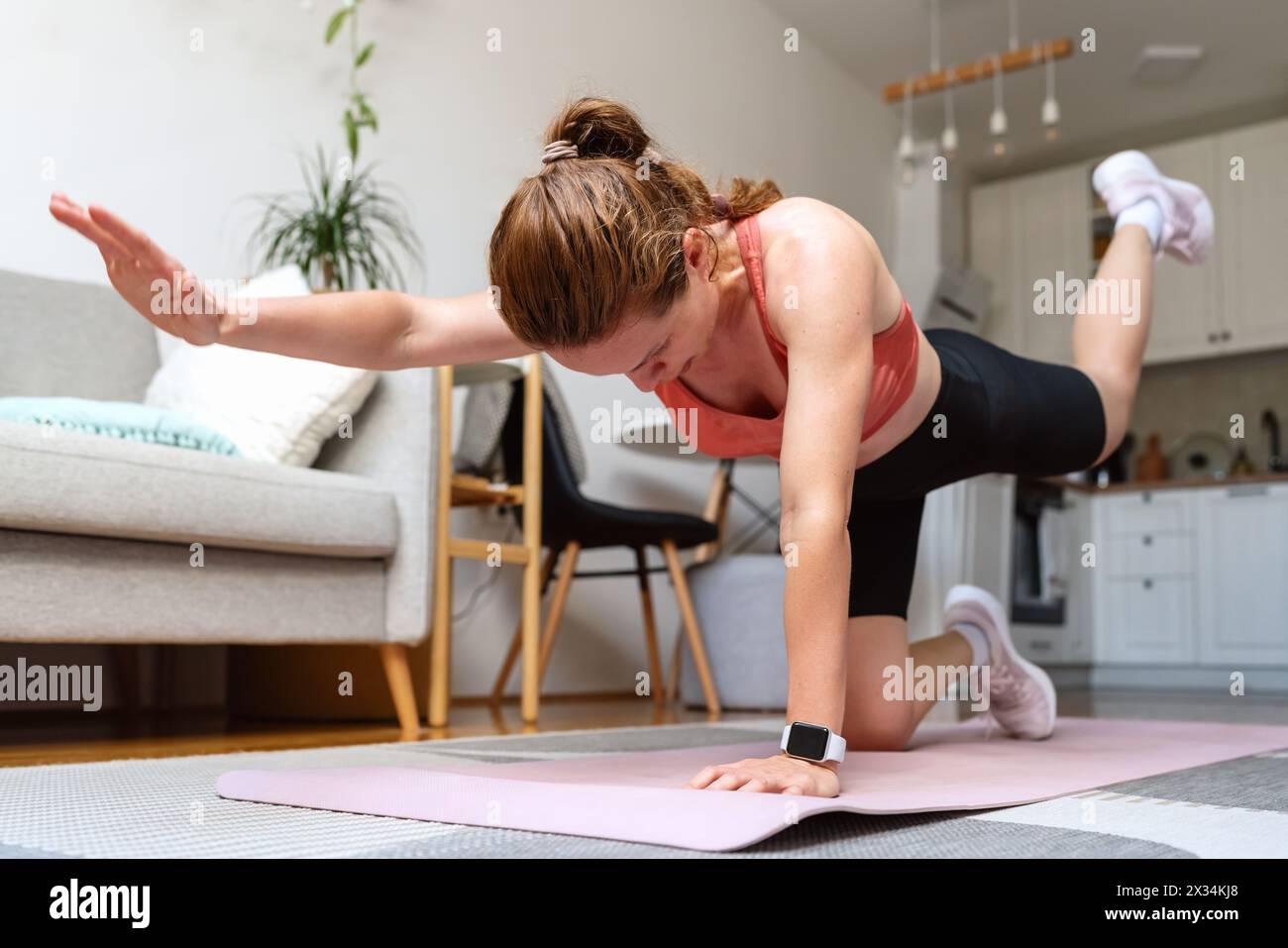 Stile di vita sportivo domestico di vera donna. Donna che fa esercizio fisico a casa. Foto Stock
