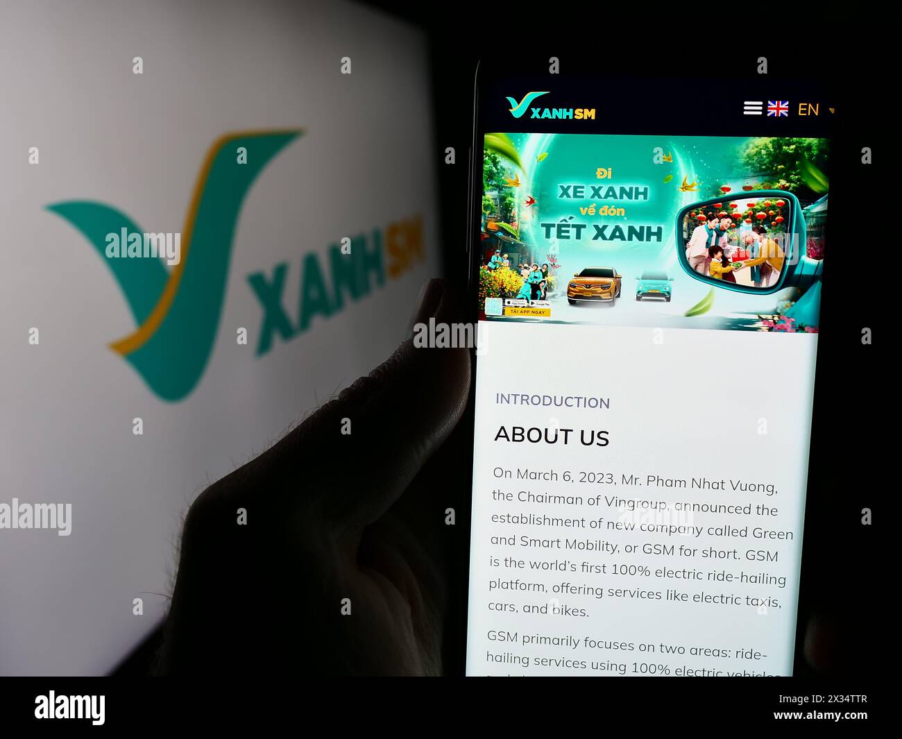 Persona che possiede uno smartphone con il sito web della società vietnamita Xanh SM davanti al logo aziendale. Messa a fuoco al centro del display del telefono. Foto Stock