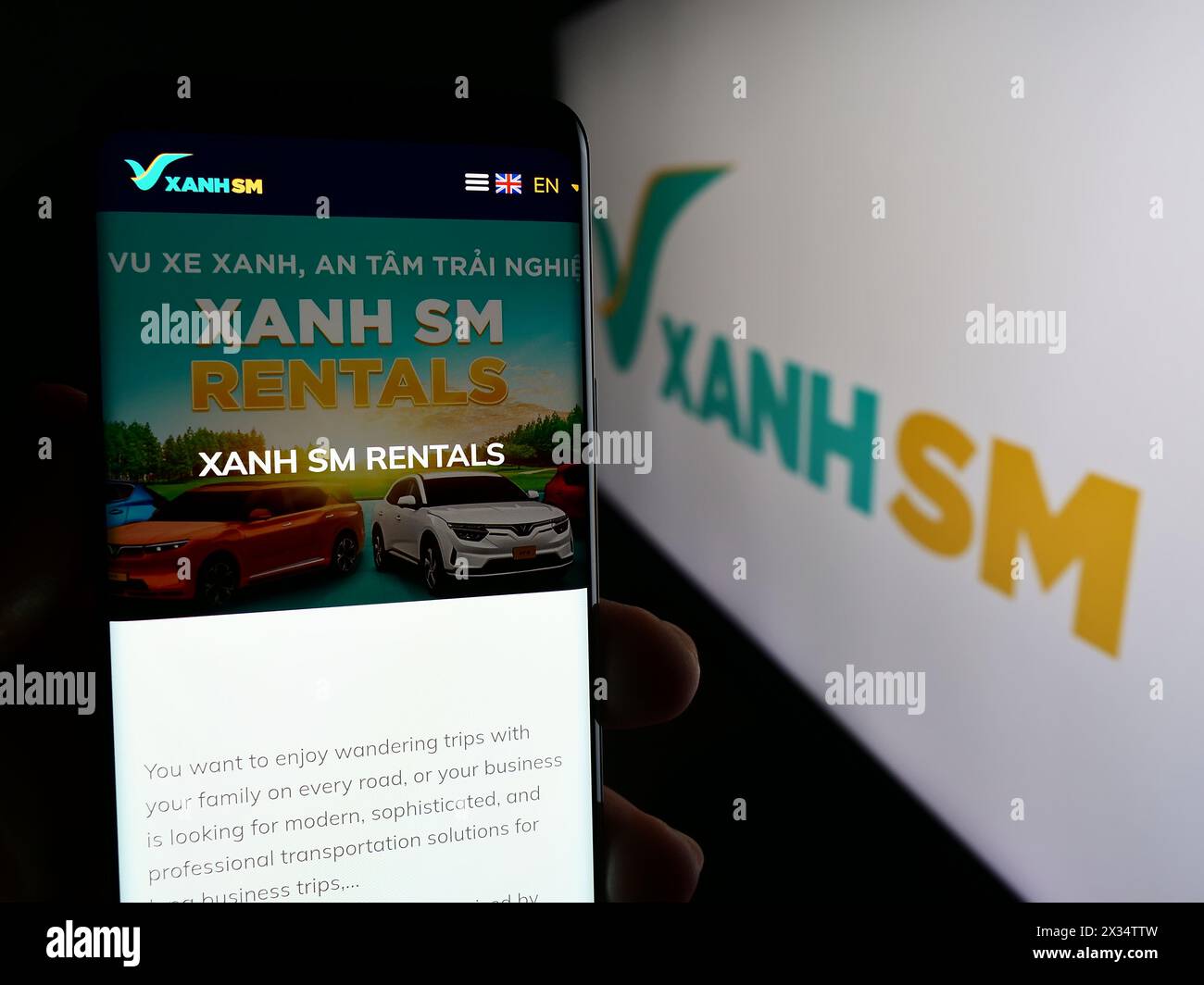 Persona che detiene un cellulare con pagina web della società vietnamita di mobilità Xanh SM davanti al logo aziendale. Messa a fuoco al centro del display del telefono. Foto Stock