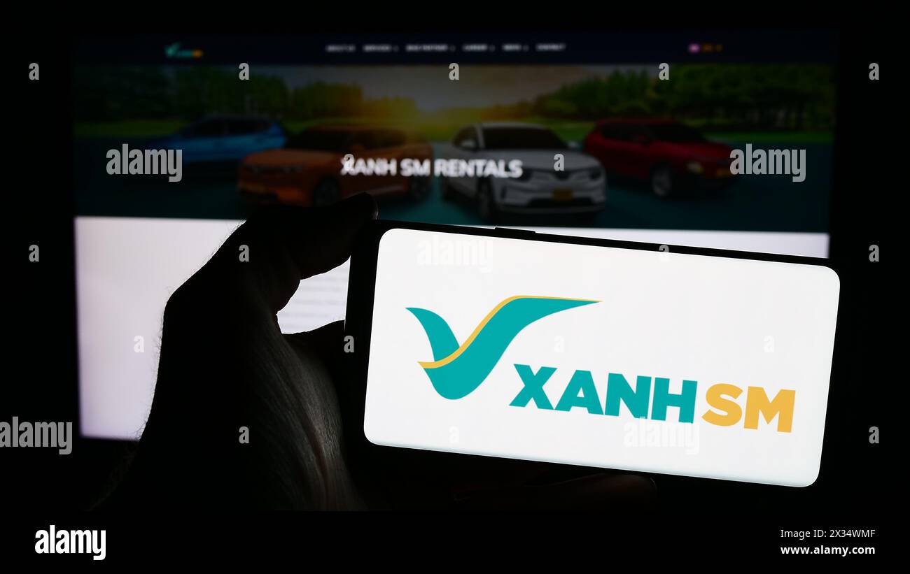 Persona che possiede uno smartphone con il logo della società vietnamita di mobilità Xanh SM davanti al sito web. Mettere a fuoco il display del telefono. Foto Stock