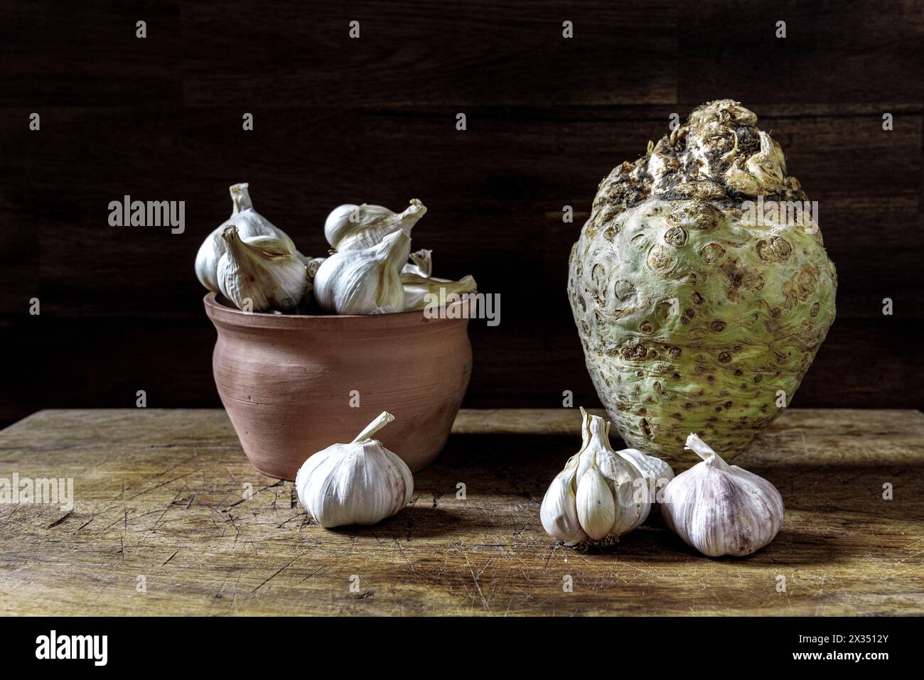 Aglio biologico in pentola e radice fresca di sedano su un tavolo rustico in legno. Background alimentare. Foto Stock