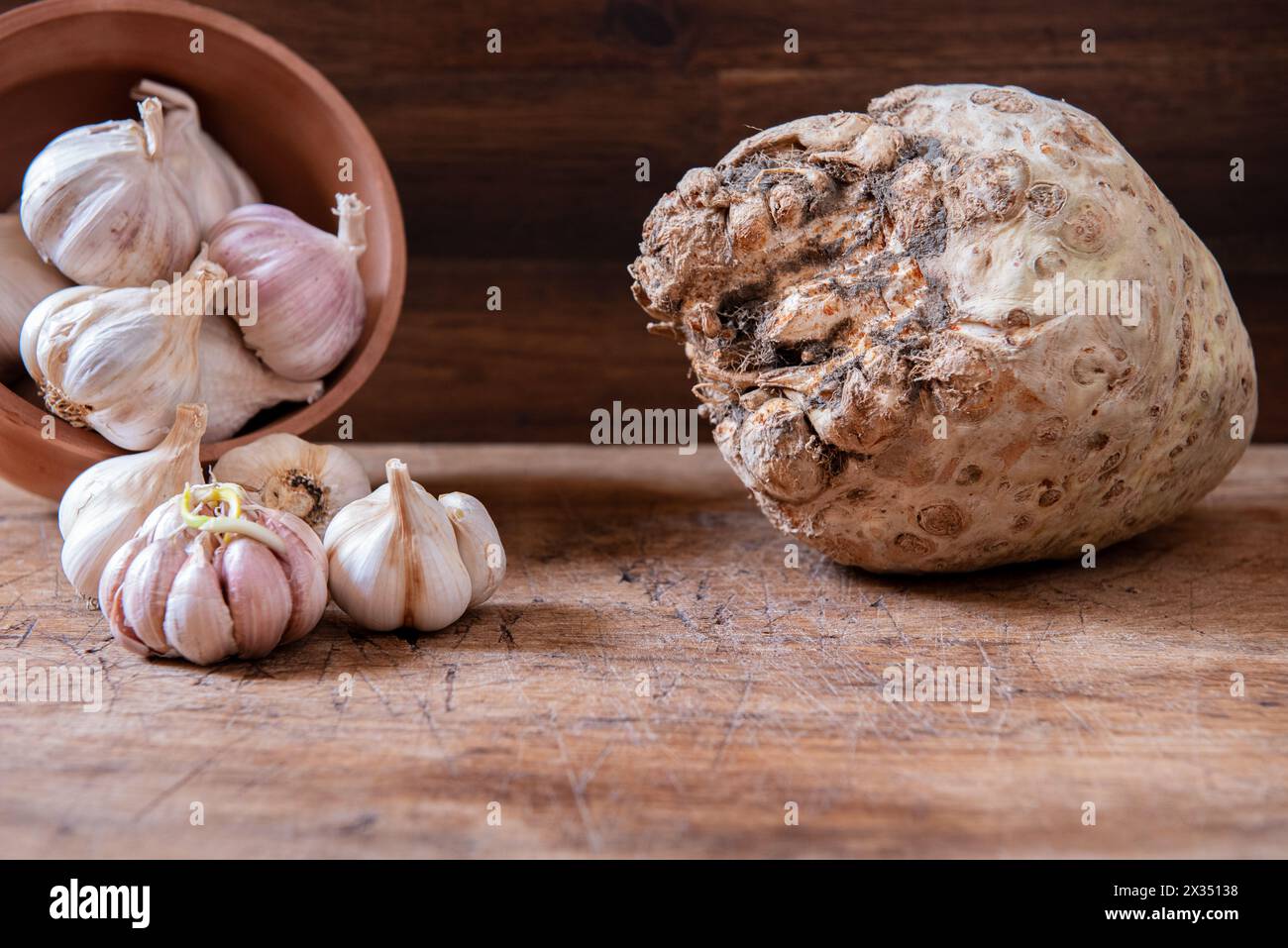 Aglio biologico in pentola e radice fresca di sedano su un tavolo rustico in legno. Background alimentare. Foto Stock