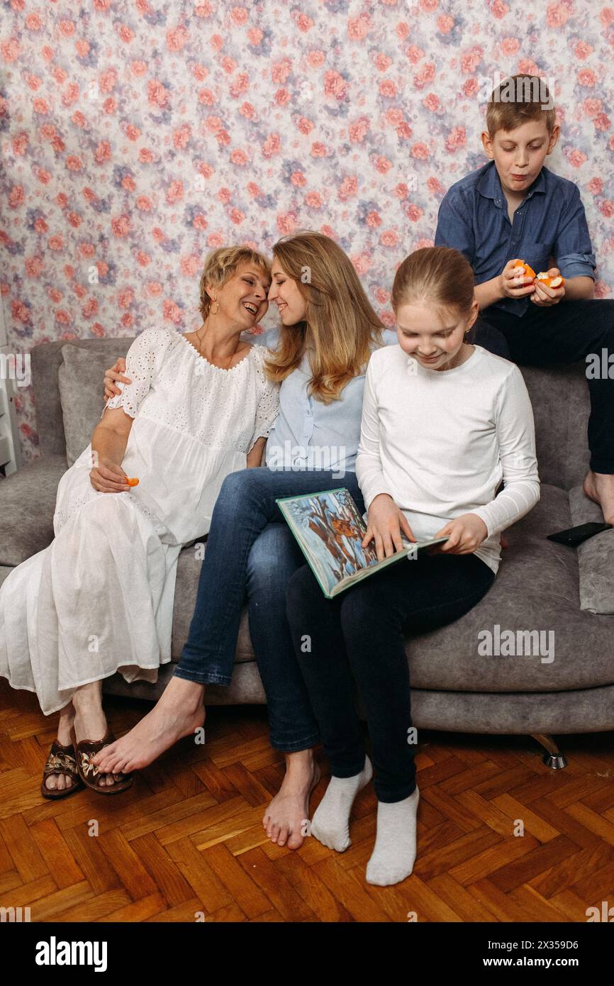 Un gruppo variegato di persone sedute comodamente su un divano, chiacchierando e rilassandosi in un ambiente informale. Foto Stock