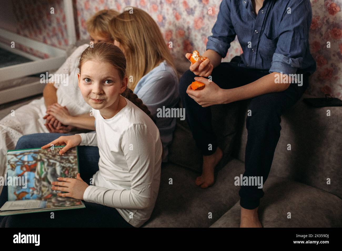Diverse persone sono sedute in cima a un divano, interagiscono casualmente o sono coinvolte in una conversazione. Foto Stock
