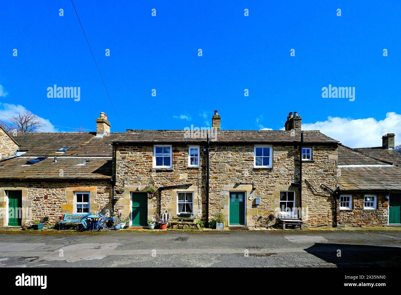 Una strada laterale attraverso il villaggio Blanchland di Northumberland che mostra lavori in pietra e spesse ardeie del tetto con cielo blu e nuvole bianche Foto Stock