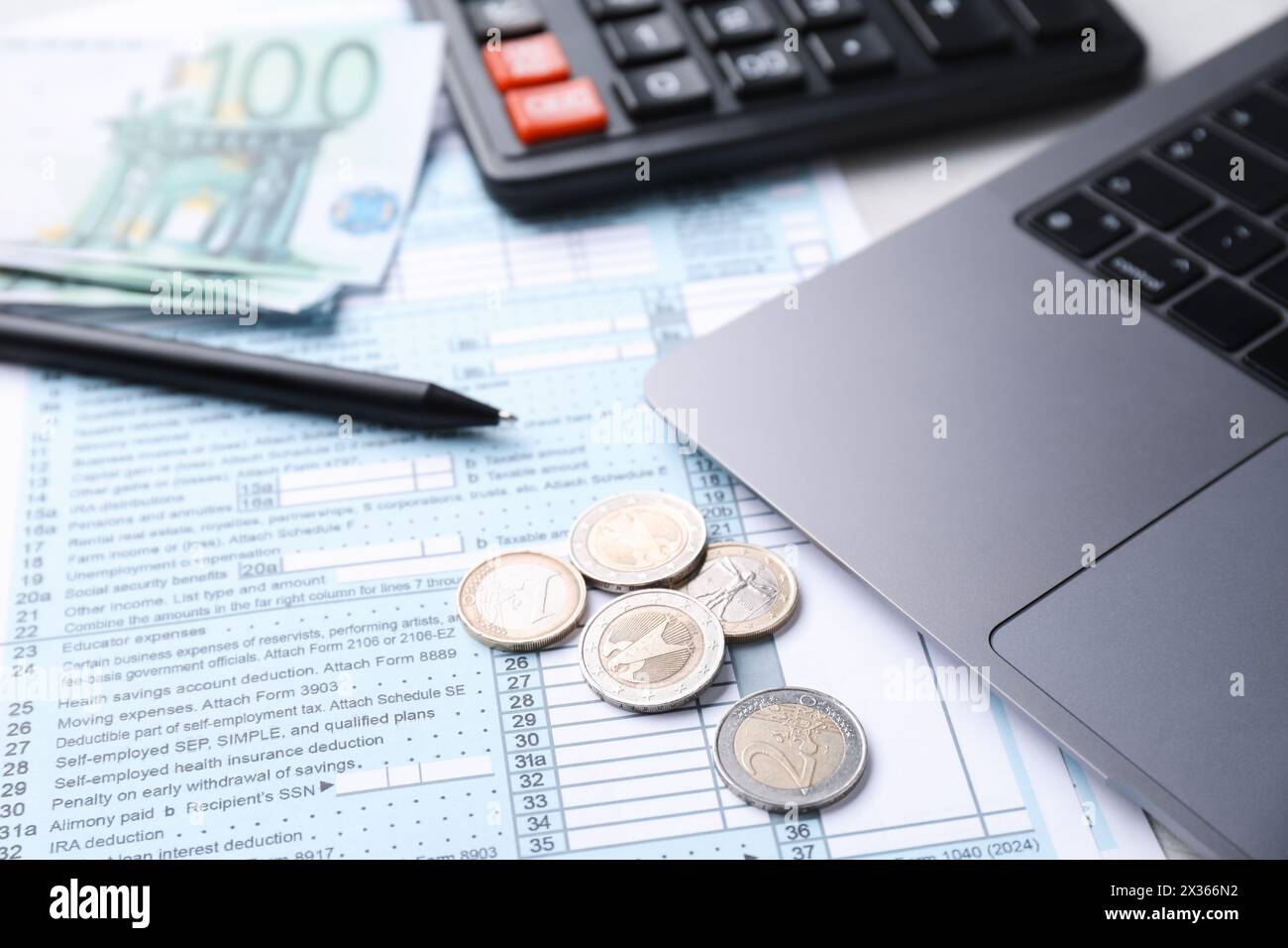 Moduli fiscali, denaro, penna, calcolatrice e laptop sul tavolo, primo piano Foto Stock