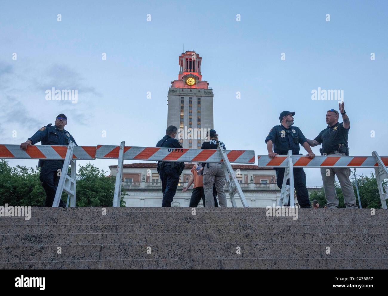 Austin Texas USA, 24 aprile 2024: Gli agenti di polizia dell'Università del Texas ad Austin sorvegliano il South Mall mentre i sostenitori del Palestine Solidarity Committee (PSC) si riuniscono per una protesta pacifica contro la guerra a Gaza in tarda serata davanti alla UT Tower. All'inizio della giornata, una marcia pacifica di protesta pro-palestinese ha portato a più di 50 arresti nel campus dopo il Texas Gov. Greg Abbott ha ordinato ai soldati del Dipartimento di pubblica sicurezza del Texas (DPS) di entrare sulla scena, aumentando le tensioni durante la protesta di un giorno. Crediti: Bob Daemmrich/Alamy Live News Foto Stock