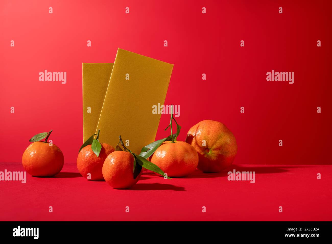 Scenografia minima di diversi tangerini e inviluppi di colore giallo visualizzati su sfondo rosso. Concetto di Capodanno lunare, sfondo moderno Foto Stock