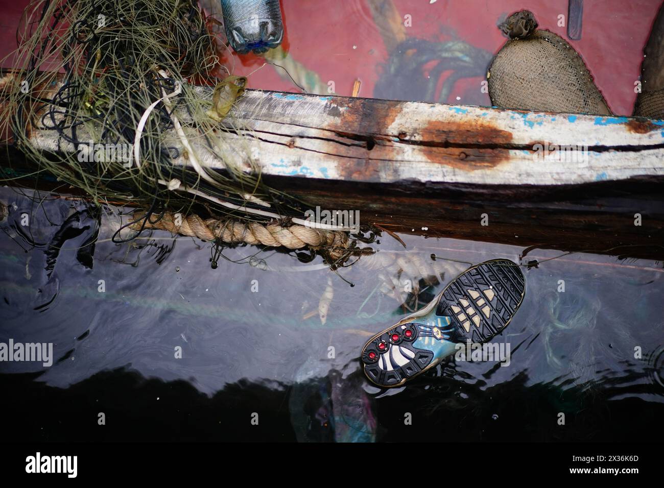 Una scarpa galleggiante nell'acqua accanto a una nave migrante affondata nel porto di Lampedusa, in Italia. Data foto: Mercoledì 24 aprile 2024. Foto Stock