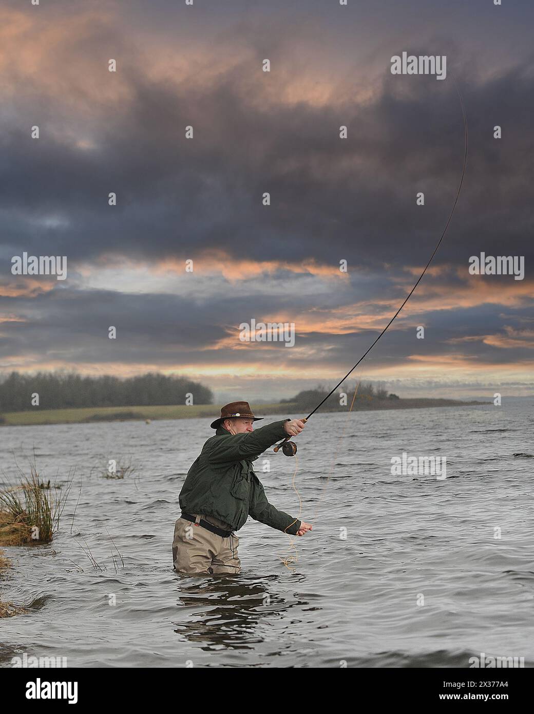 l'uomo pesca con la mosca al tramonto Foto Stock