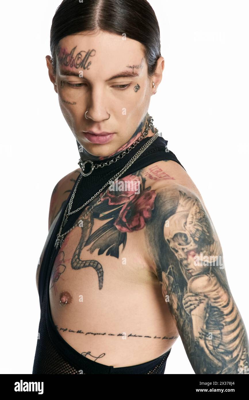 Un giovane uomo elegante che mostra con orgoglio un tatuaggio scheletrico in uno studio su uno sfondo grigio. Foto Stock