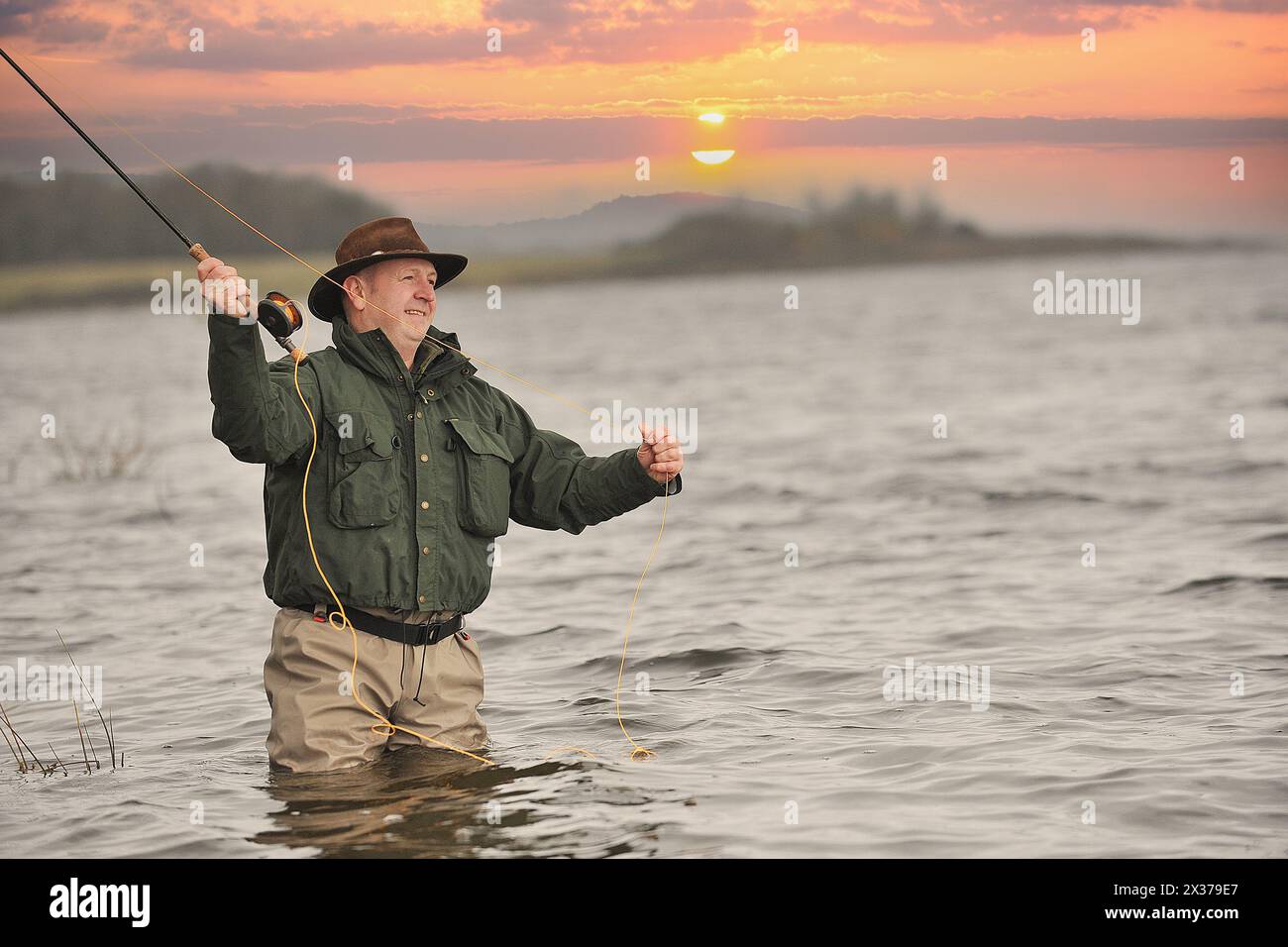 l'uomo pesca con la mosca al tramonto Foto Stock