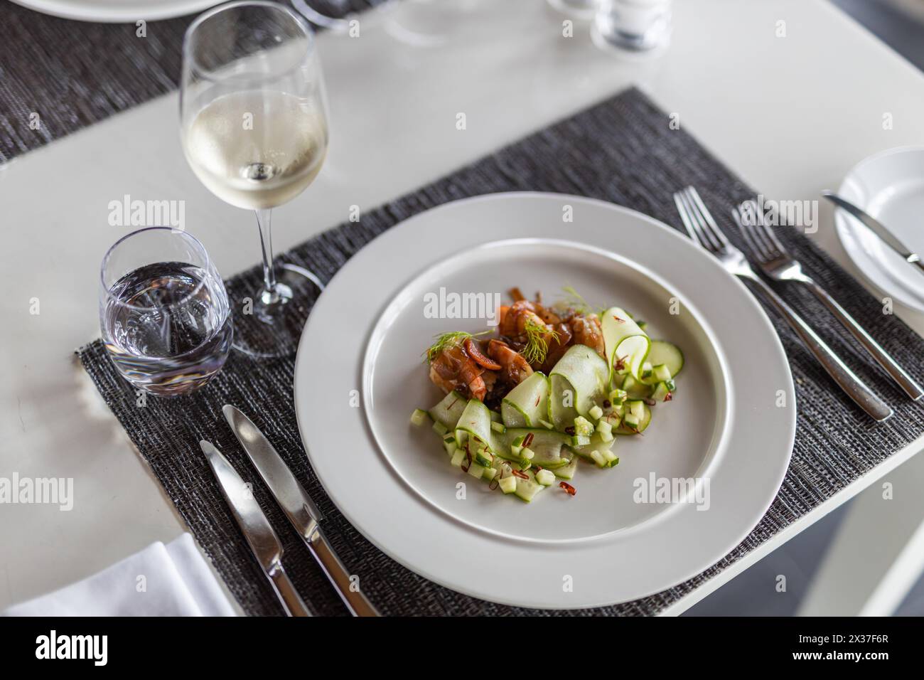 Delizioso piatto di gamberi servito con verdure fresche su piatto bianco. Elegante antipasto di gamberi, arrotondati di cetrioli, guarniti con rametti di aneto freschi. Foto Stock