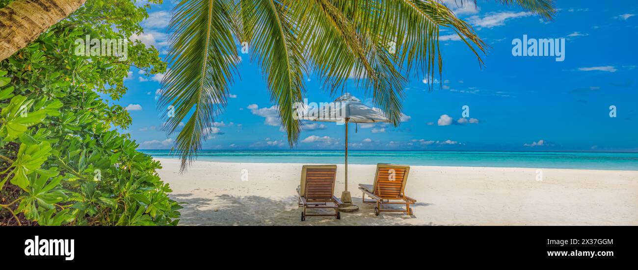 Bellissimo cielo panoramico di sabbia marina. Spiaggia tropicale rilassante, soleggiato paesaggio estivo dell'isola. Amore coppia sedie ombrello palma lascia romantica costa. Lusso Foto Stock