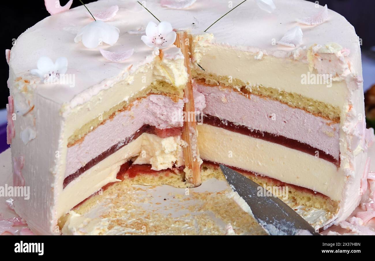 Torta con un pezzo tagliato sul tavolo delle feste Foto Stock