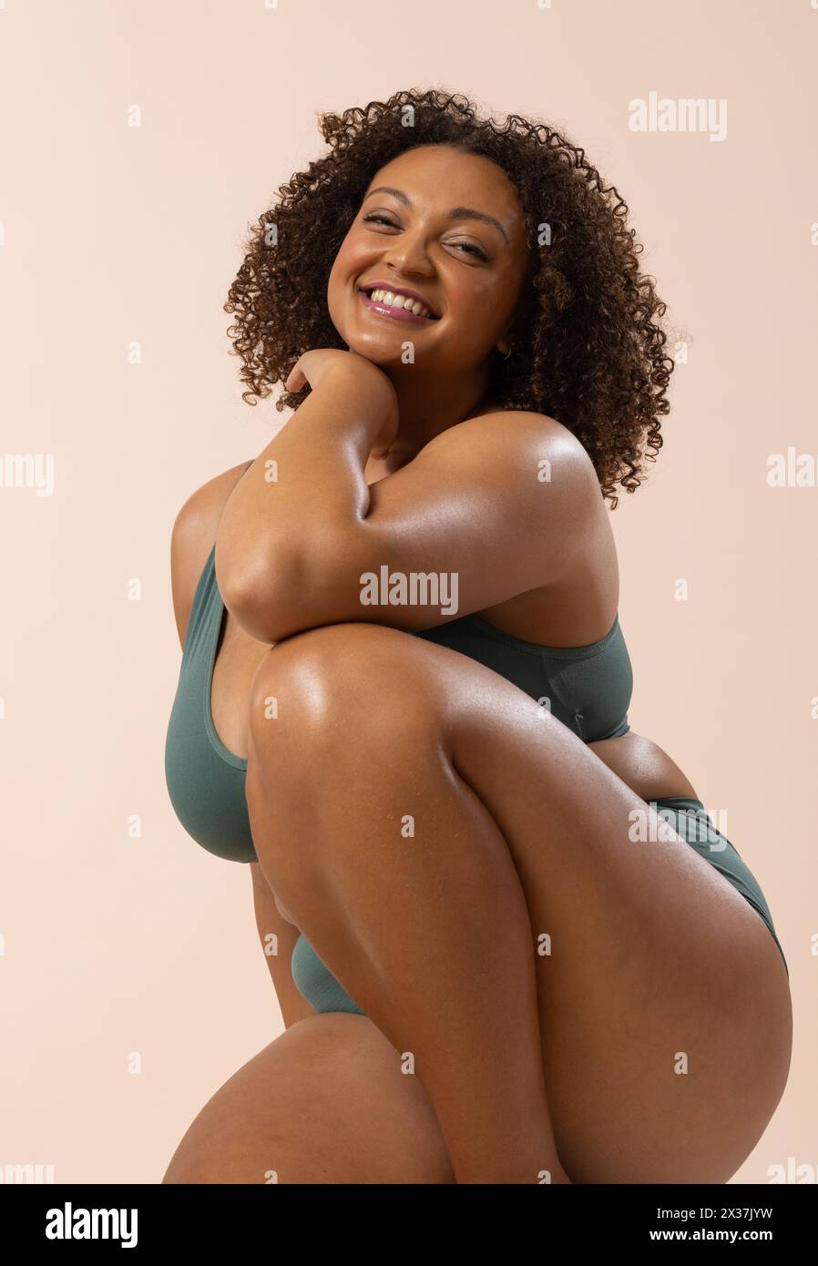 Modello birazziale giovane donna Plus-size in stile sportivo color tè si posa su sfondo beige Foto Stock