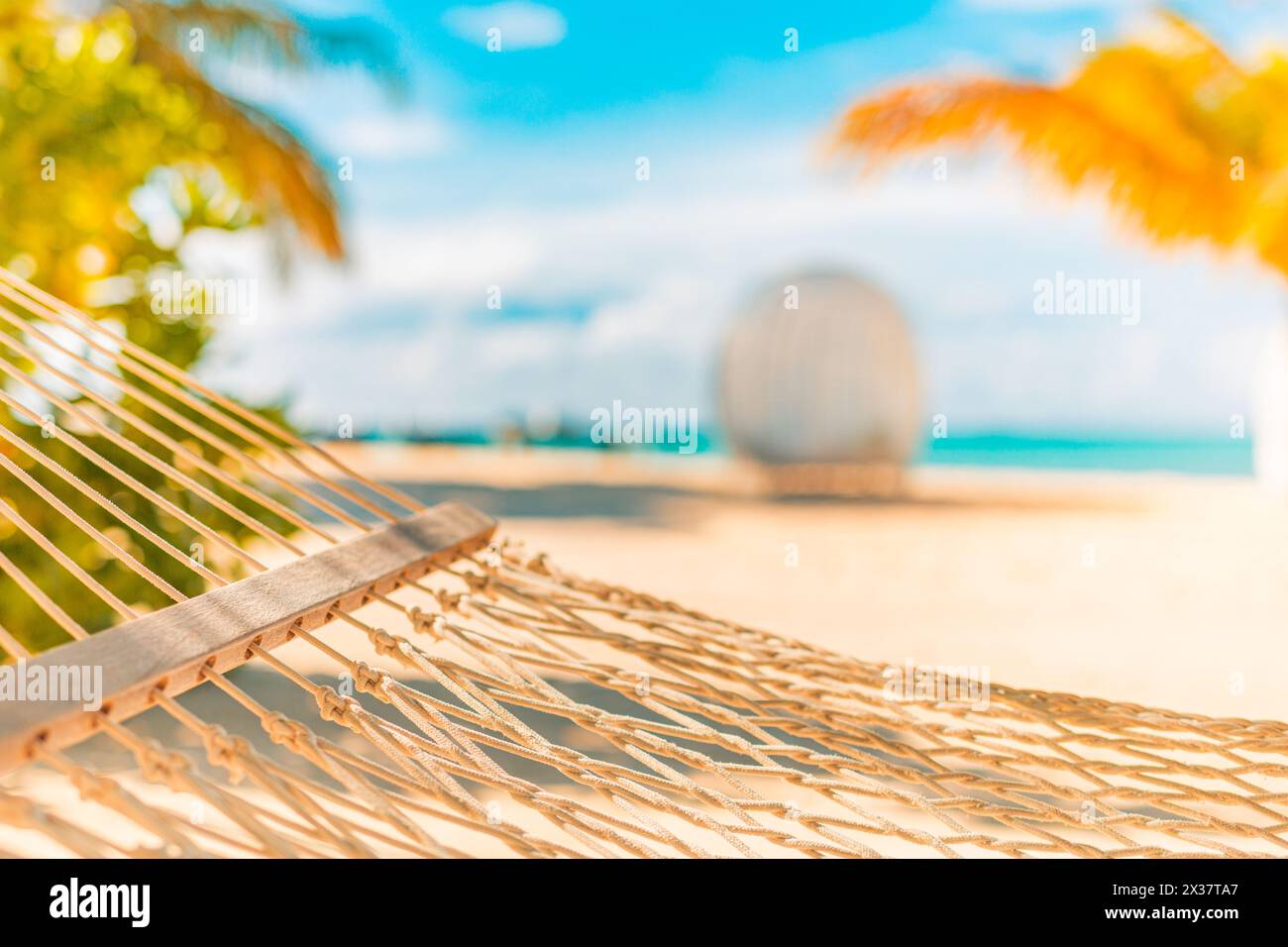 Spiaggia tranquilla e rilassante con il paesaggio estivo dell'isola con altalena o amaca sulla palma, cielo marino tropicale e soleggiato. Una splendida vacanza panoramica sulla spiaggia Foto Stock