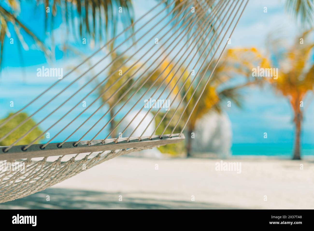 Spiaggia tranquilla e rilassante con il paesaggio estivo dell'isola con altalena o amaca sulla palma, cielo marino tropicale e soleggiato. Una splendida vacanza panoramica sulla spiaggia Foto Stock