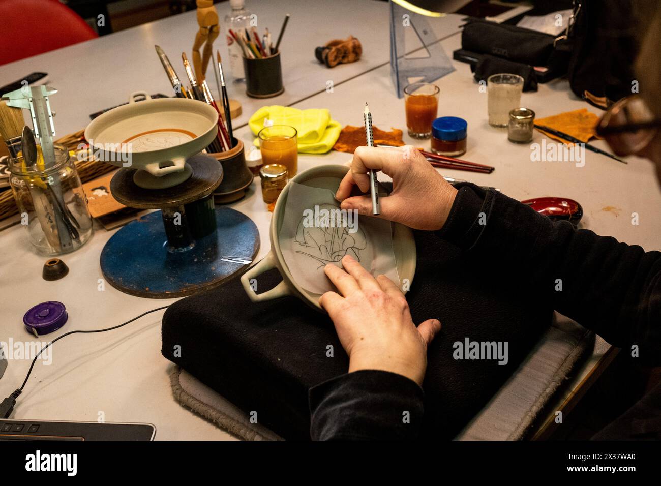 Una donna si prepara con cura a dipingere un vaso ispirato alle anfore greche prima di essere dipinto nelle botteghe del Nero Attico ad Atene nel AT Foto Stock