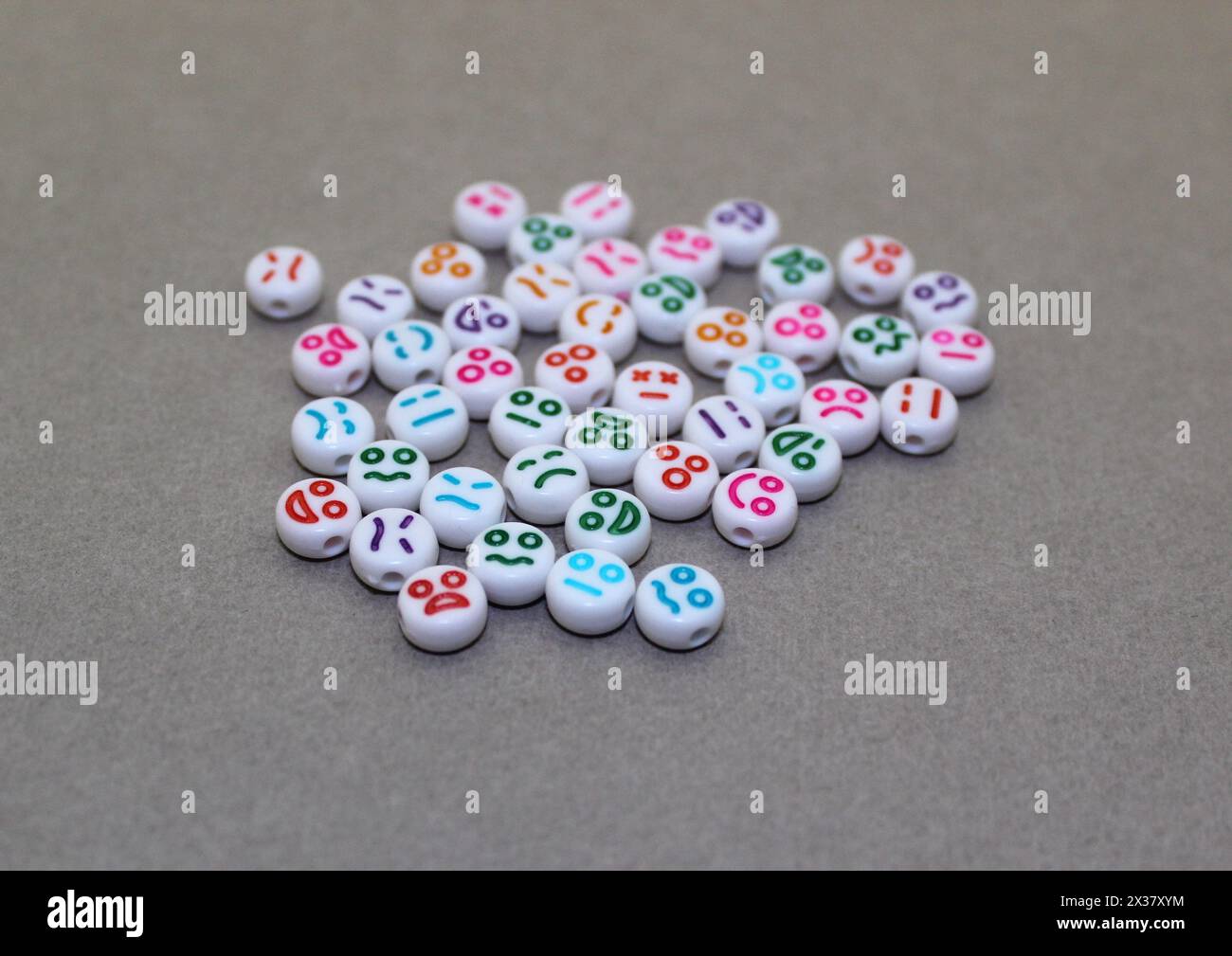 Perline decorative in plastica con volti divertenti. Pietre decorative bianche per la collana. Foto Stock