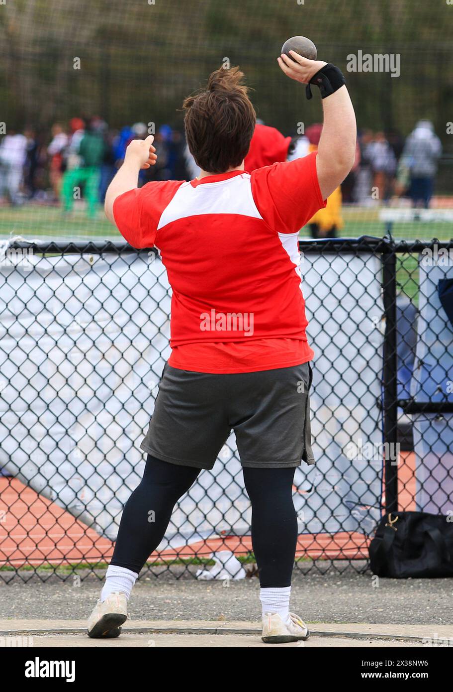 Vista posteriore di un liceale pronto a lanciare il colpo messo in una gara all'aperto. Foto Stock