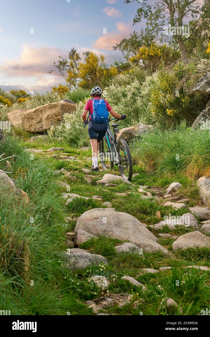 Donna anziana attiva in bicicletta con la sua mountain bike elettrica nel paesaggio accidentato del Parco Nazionale Serra de São Mamede vicino a Marvao, Portogallo centrale Foto Stock